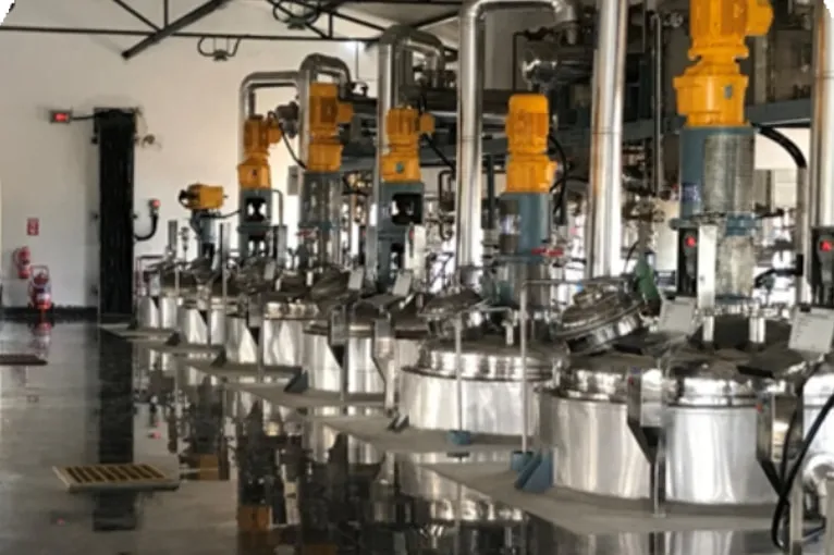 Row of stainless steel reactors with agitator drives in the plant hall